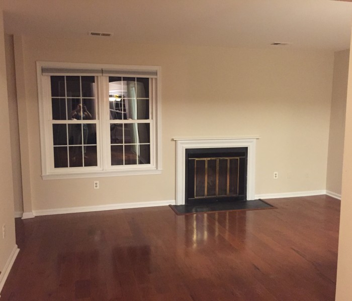 Empty living room with hardwood floors and a fireplace.