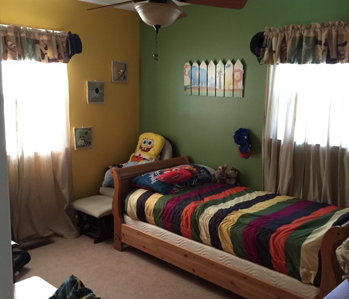 A child's bedroom with a bed and a bedside table.