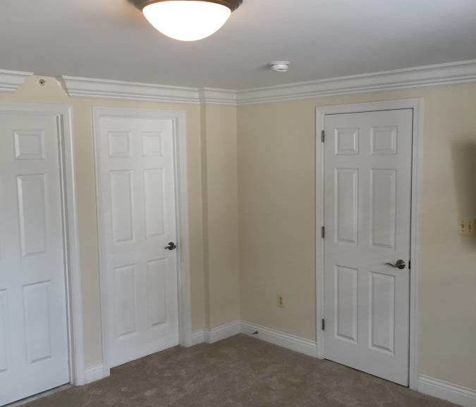 An empty room with two doors and a ceiling fan.
