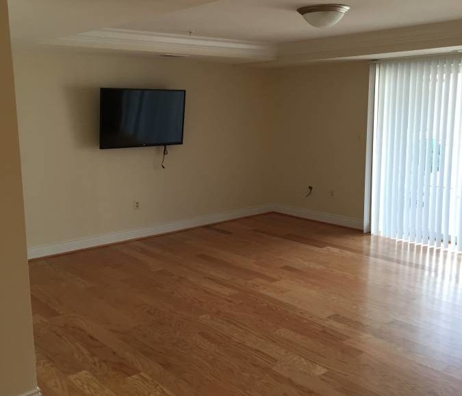 Empty living room with hardwood floors and a tv.
