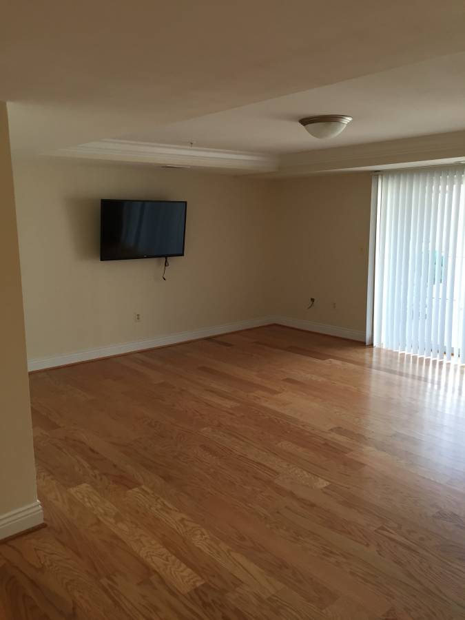 Empty living room with hardwood floors and a tv.