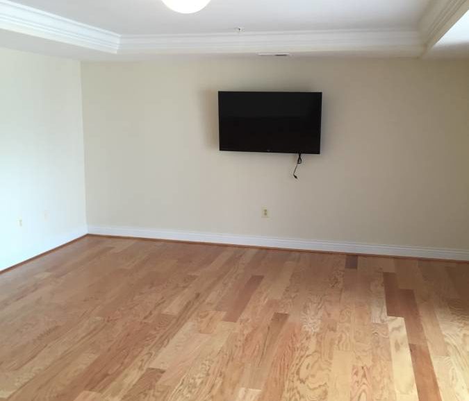 An empty room with hardwood floors and a tv.