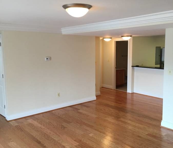An empty living room with hardwood floors.