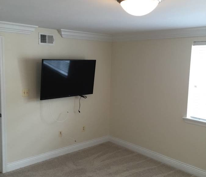 An empty room with a tv on the wall.