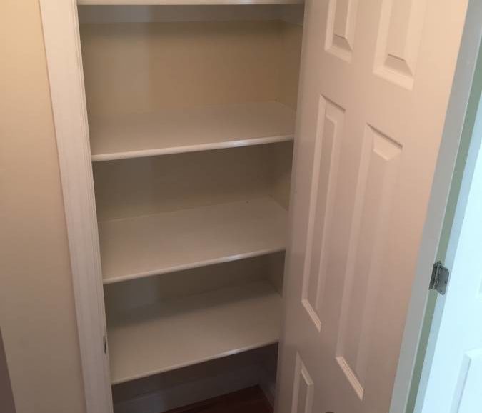 A white closet with shelves in it.