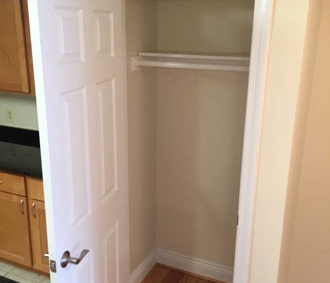 An empty room with a closet and cabinets.