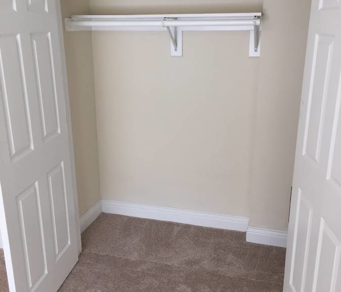 An empty closet in a room with a door.