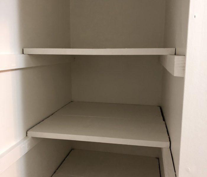 An Empty Wooden Shelf With White Cabinets