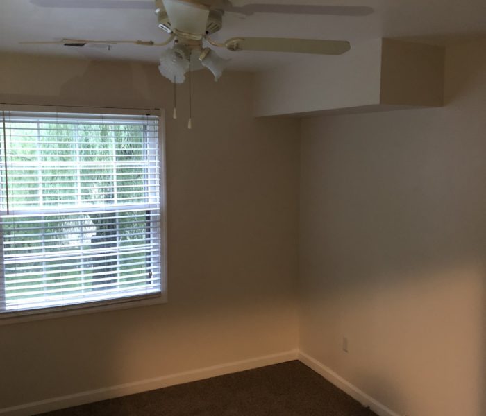 An Empty Room With Shutters and a Fan