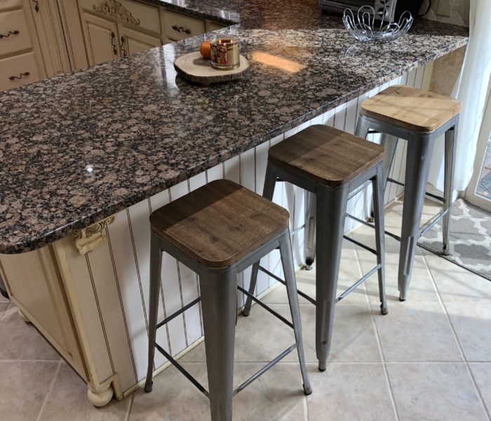 A kitchen with a granite counter top and stools.