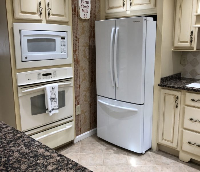 A white refrigerator in a kitchen with granite counter tops.