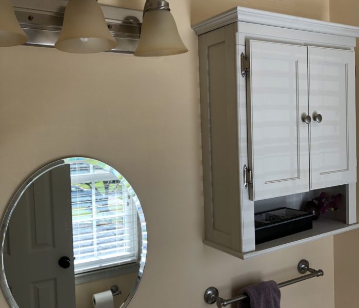 A bathroom with a white cabinet and a mirror.