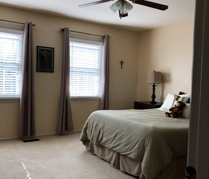 A bed in a bedroom with a ceiling fan.